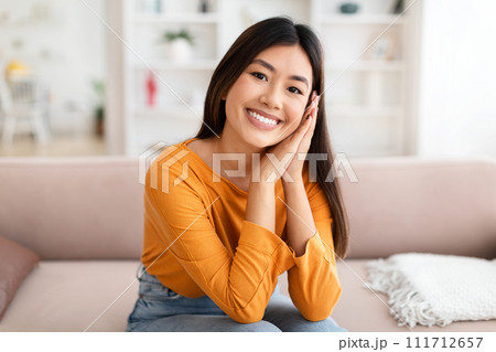 Cute pretty chinese lady sitting on couch at home Cute pretty chinese lady sitting on couch at home 111712657