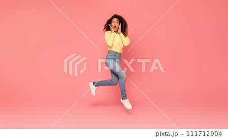 Surprised black woman jumps, touches cheeks, excited on pink backdrop 111712904