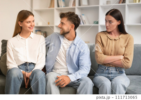man hugs girlfriend while another woman looks with jealousy indoor 111713065