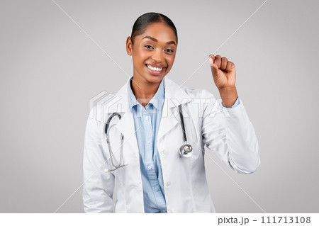 Glad young black lady doctor show pill capsule, recommends treatment 111713108