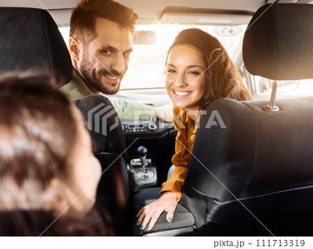 Joyful couple in car, turning back to child and smiling 111713319