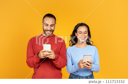 Portrait of cheerful couple holding their smartphones and playing game Portrait of cheerful couple holding their smartphones and playing game 111713332