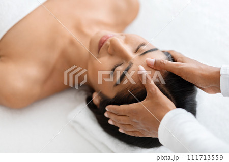 Professional masseur soothes the brow of young Indian beautiful lady 111713559