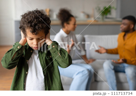 Child boy covers ears while parents argue in the background 111713734