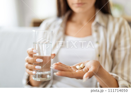 Young Woman Holding Pile Of Pills In Hand And Glass Of Water 111714050