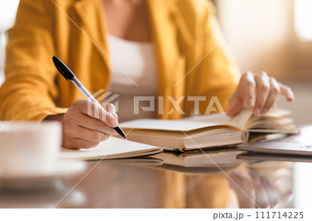 Unrecognizable businesswoman doing paperwork closeup of hands taking notes indoor Unrecognizable businesswoman doing paperwork closeup of hands taking notes indoor 111714225