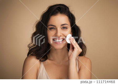 Woman removes makeup from the face with a cotton pad Woman removes makeup from the face with a cotton pad 111714468