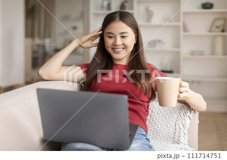 Domestic Leisure. Young Asian Woman Relaxing With Coffee And Laptop At Home Domestic Leisure. Young Asian Woman Relaxing With Coffee And Laptop At Home 111714751