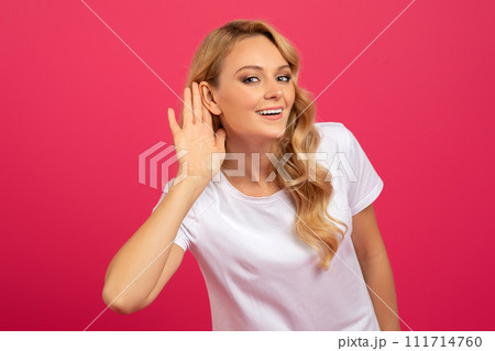 Blonde Woman Listening Holding Hand Near Ear Over Pink Background 111714760