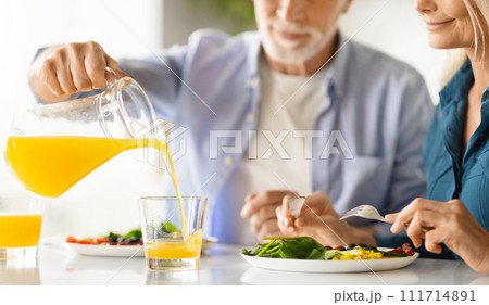 Elderly spouses having breakfast together in kitchen, cropped shot 111714891
