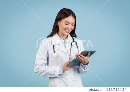 Young female doctor using digital tablet, smiling 111715154