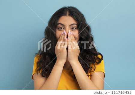 Emotional young indian woman covering her mouth Emotional young indian woman covering her mouth 111715453