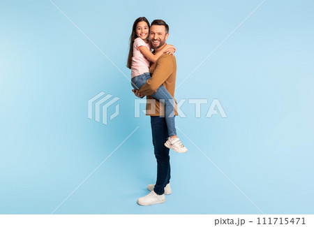 Daughter Embracing Dad As He Holds Her In Arms, Studio Daughter Embracing Dad As He Holds Her In Arms, Studio 111715471