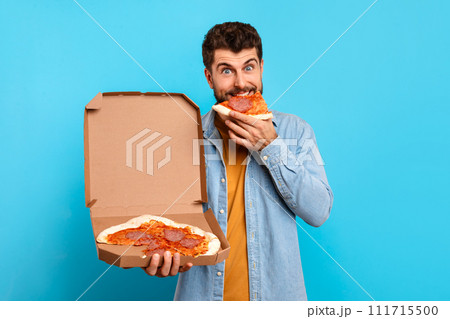 man enjoys slice of pizza holding carton delivery box, studio 111715500