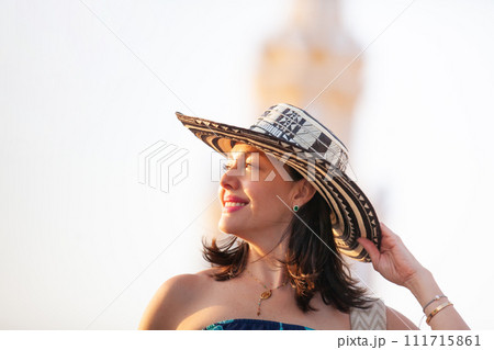 Beautiful woman wearing the traditional Colombian hat called Sombrero Vueltiao at the Clock Tower on the historical streets of the Cartagena de Indias walled city 111715861