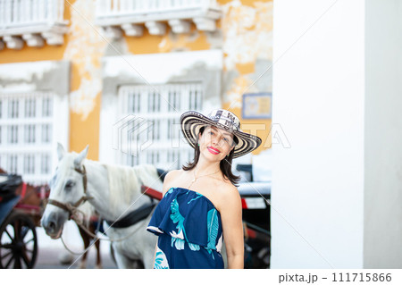 Beautiful woman wearing the traditional Colombian hat called Sombrero Vueltiao at the Customs Square on the historical streets of the Cartagena de Indias walled city 111715866