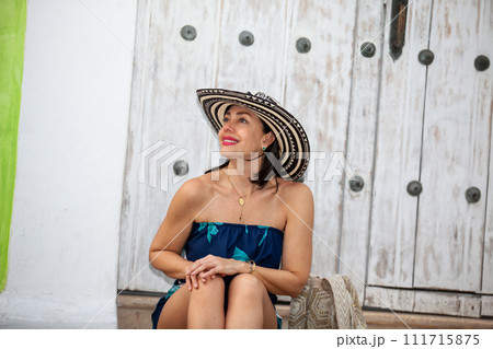 Beautiful woman wearing the traditional Colombian hat called Sombrero Vueltiao at the historical streets of the Cartagena de Indias walled city 111715875