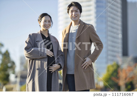 公園を手を繋いで歩く妊婦と男性 111716067
