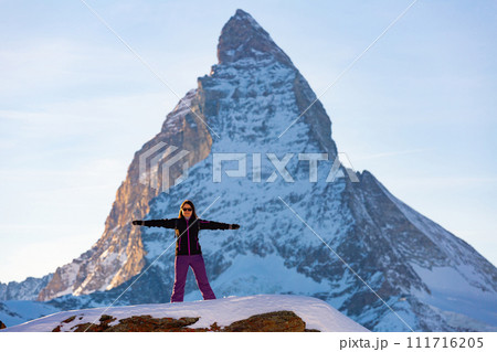 Cheerful female hiker posing against rocky Matterhorn peak in winter 111716205