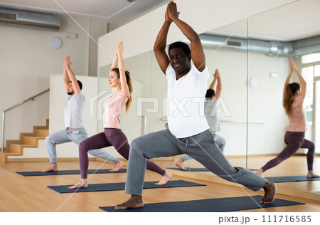 African american standing in Ashta Chandrasana with hands in prayer above head 111716585
