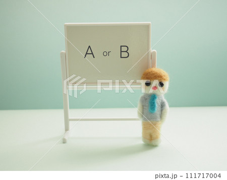 ホワイトボードにAorBの文字と羊毛フェルトの男性 111717004