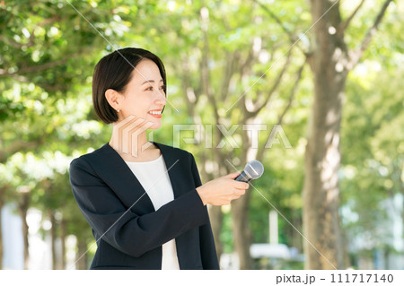 屋外でマイクを持つ女性アナウンサー 111717140