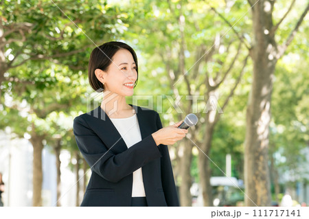 屋外でマイクを持つ女性アナウンサー 111717141