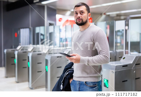 Male passenger in casual clothing near baffle gate in underground platform closeup Male passenger in casual clothing near baffle gate in underground platform closeup 111717182