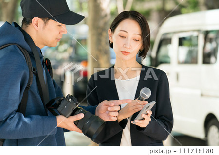 屋外で取材をする記者とカメラマン 屋外で取材をする記者とカメラマン 111718180