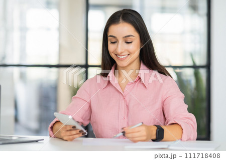 Smiling millennial european lady manager typing on phone, chatting, planning project 111718408