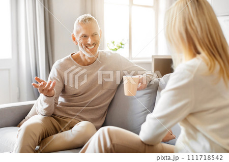 Happy senior man and woman drinking coffee, chatting at home Happy senior man and woman drinking coffee, chatting at home 111718542