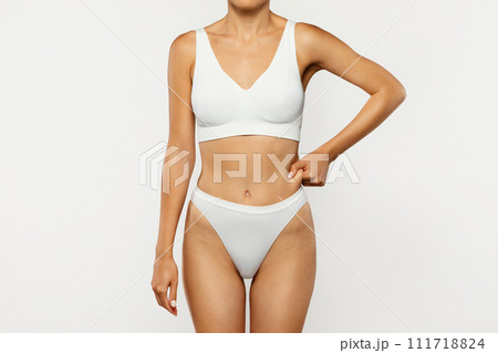 Young european woman in underwear touches fold of skin fat at waist Young european woman in underwear touches fold of skin fat at waist 111718824