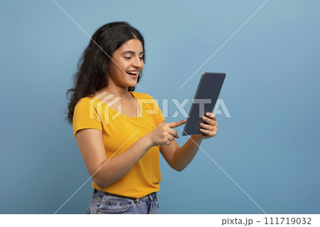 Happy young indian lady using digital tablet, chatting with friends 111719032