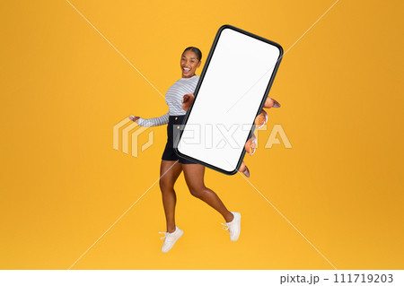 Excited Black Young Woman Holding Smartphone Blank Screen Jumping, Studio 111719203