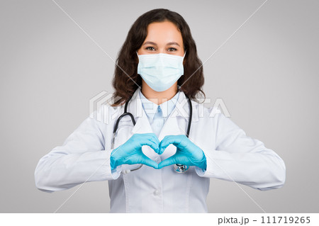 Woman doctor in mask making heart sign with hands Woman doctor in mask making heart sign with hands 111719265