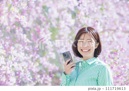 満開の桜をスマートフォンで撮影する女性 111719613