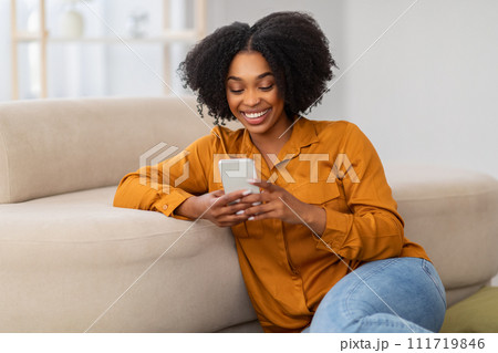 Cheerful millennial curly african american woman chatting on phone 111719846