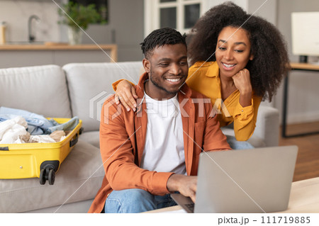Happy black travelers couple planning vacation travel with laptop indoors Happy black travelers couple planning vacation travel with laptop indoors 111719885