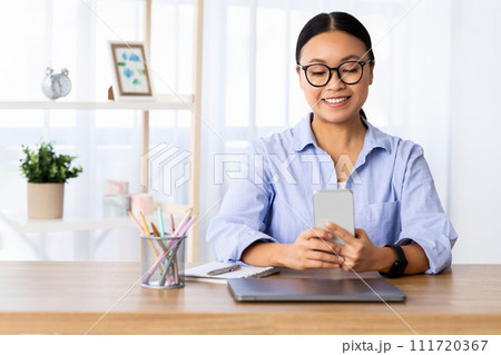 Cheerful asian businesswoman working from home, multitasking Cheerful asian businesswoman working from home, multitasking 111720367