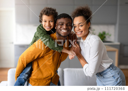 Joyful black family with young boy piggybacking on father's back 111720368