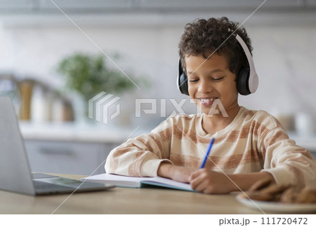Online Lesson. Black Boy In Wireless Headphones Study With Laptop At Home Online Lesson. Black Boy In Wireless Headphones Study With Laptop At Home 111720472