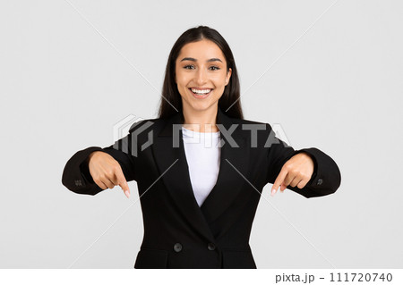 Confident european businesswoman pointing downwards with both hands 111720740
