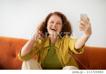 Radiant senior woman laughing joyfully while taking selfie on smartphone at home Radiant senior woman laughing joyfully while taking selfie on smartphone at home 111720968