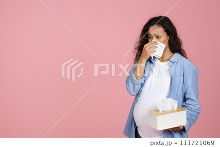 Pregnant woman suffering from snotty nose, pink background Pregnant woman suffering from snotty nose, pink background 111721069