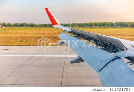 View of airplane wing, blue skies and green land during landing. Airplane window view. View of airplane wing, blue skies and green land during landing. Airplane window view. 111721708