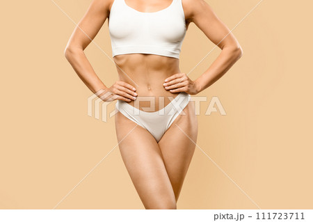 Toned young woman in white underwear standing with hands on waist Toned young woman in white underwear standing with hands on waist 111723711