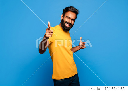 Excited indian man in yellow pointing with both hands to camera Excited indian man in yellow pointing with both hands to camera 111724125
