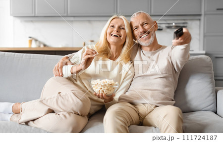 Joyful old man and woman couple watching TV at home Joyful old man and woman couple watching TV at home 111724187