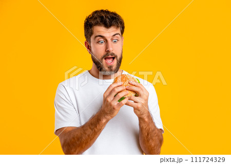 Excited Millennial Man Looking At Burger With Open Mouth, Studio Excited Millennial Man Looking At Burger With Open Mouth, Studio 111724329