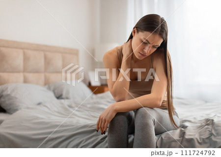 Woman sitting on bed feeling unwell Woman sitting on bed feeling unwell 111724792